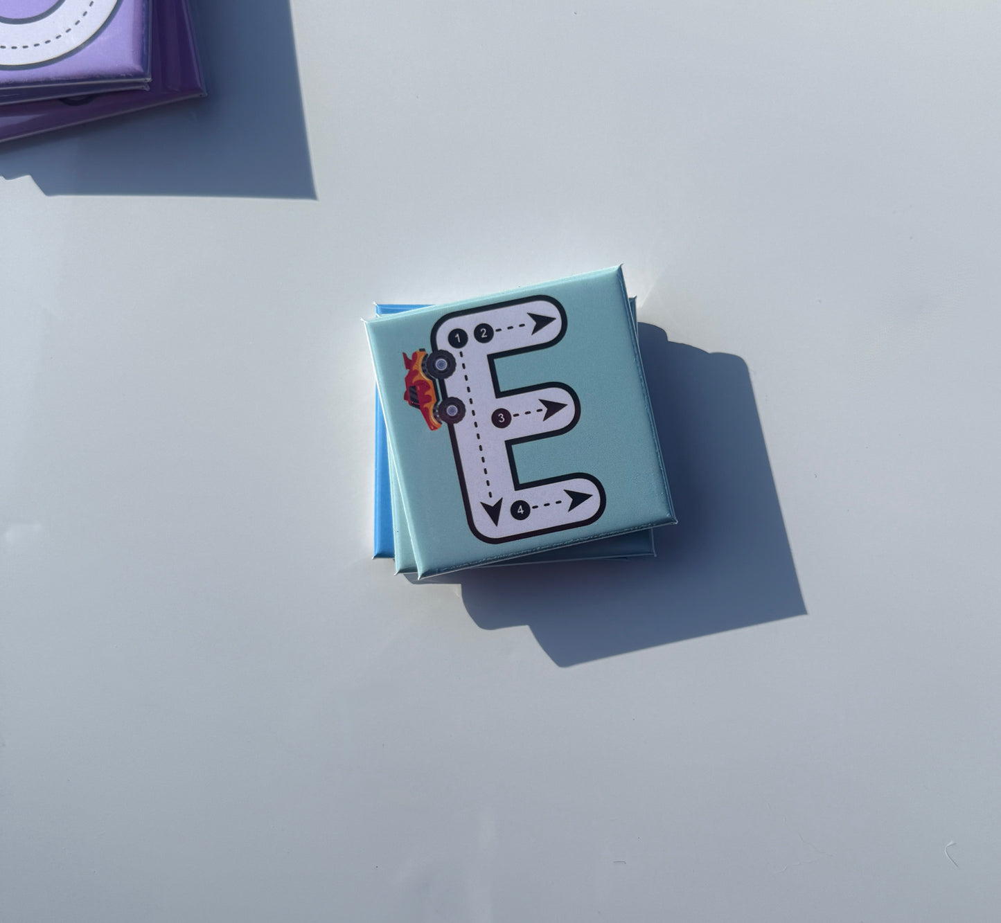 Small blue magnet with letter 'E' design on a light gray background