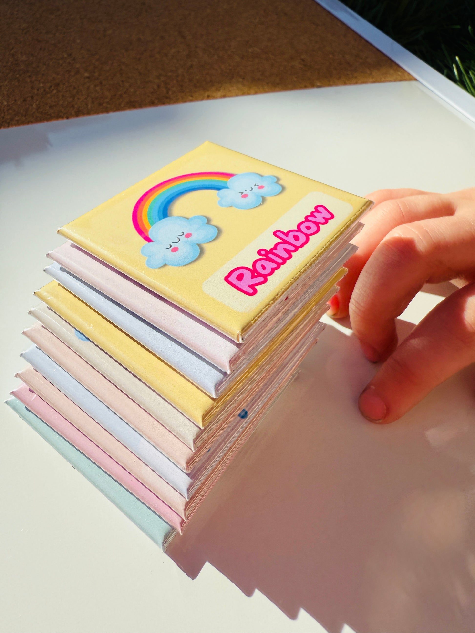 Stack of handmade weather magnets for kids with rainbow design on top