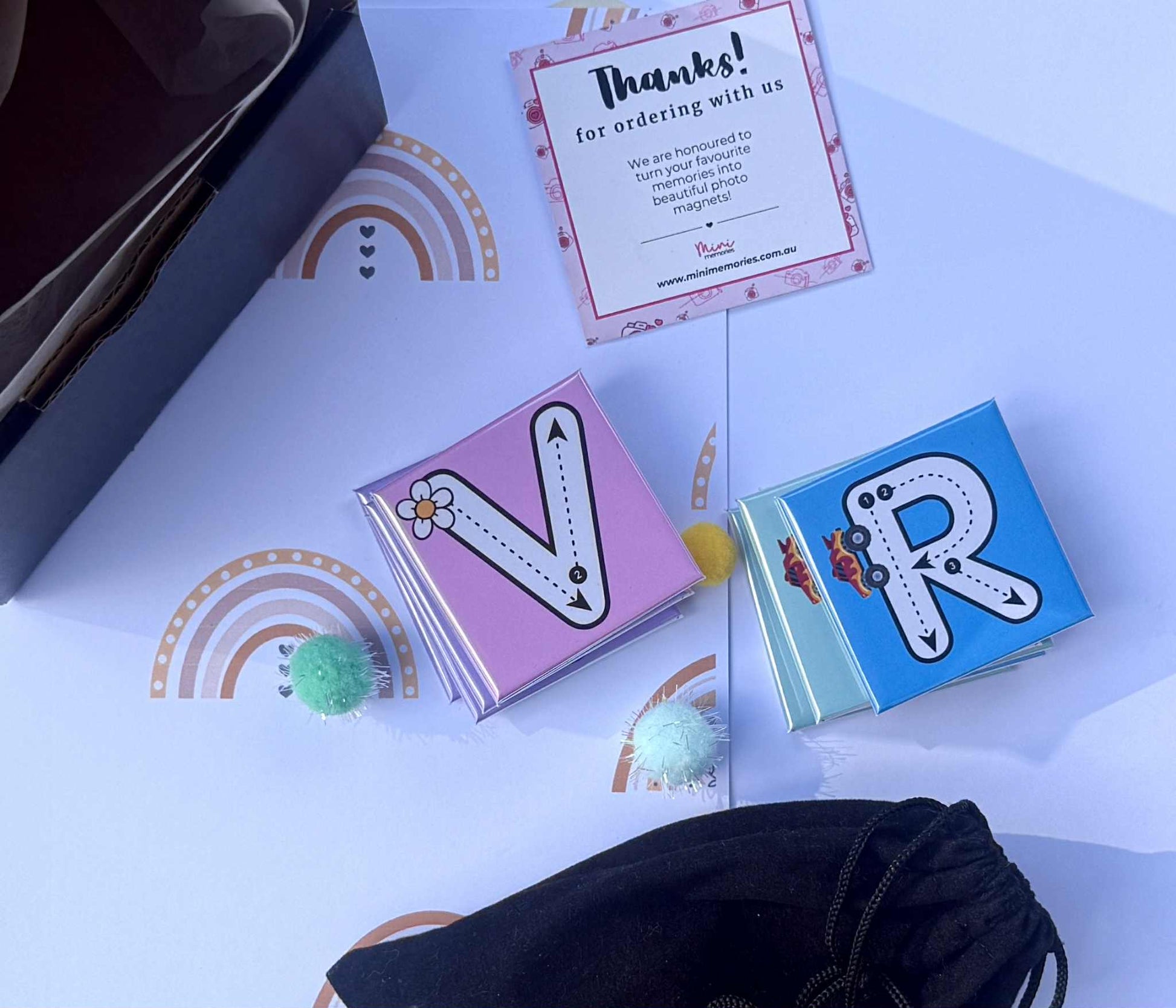 Two small magnets with letter 'V' and 'R' designs on a white surface with rainbow patterns.