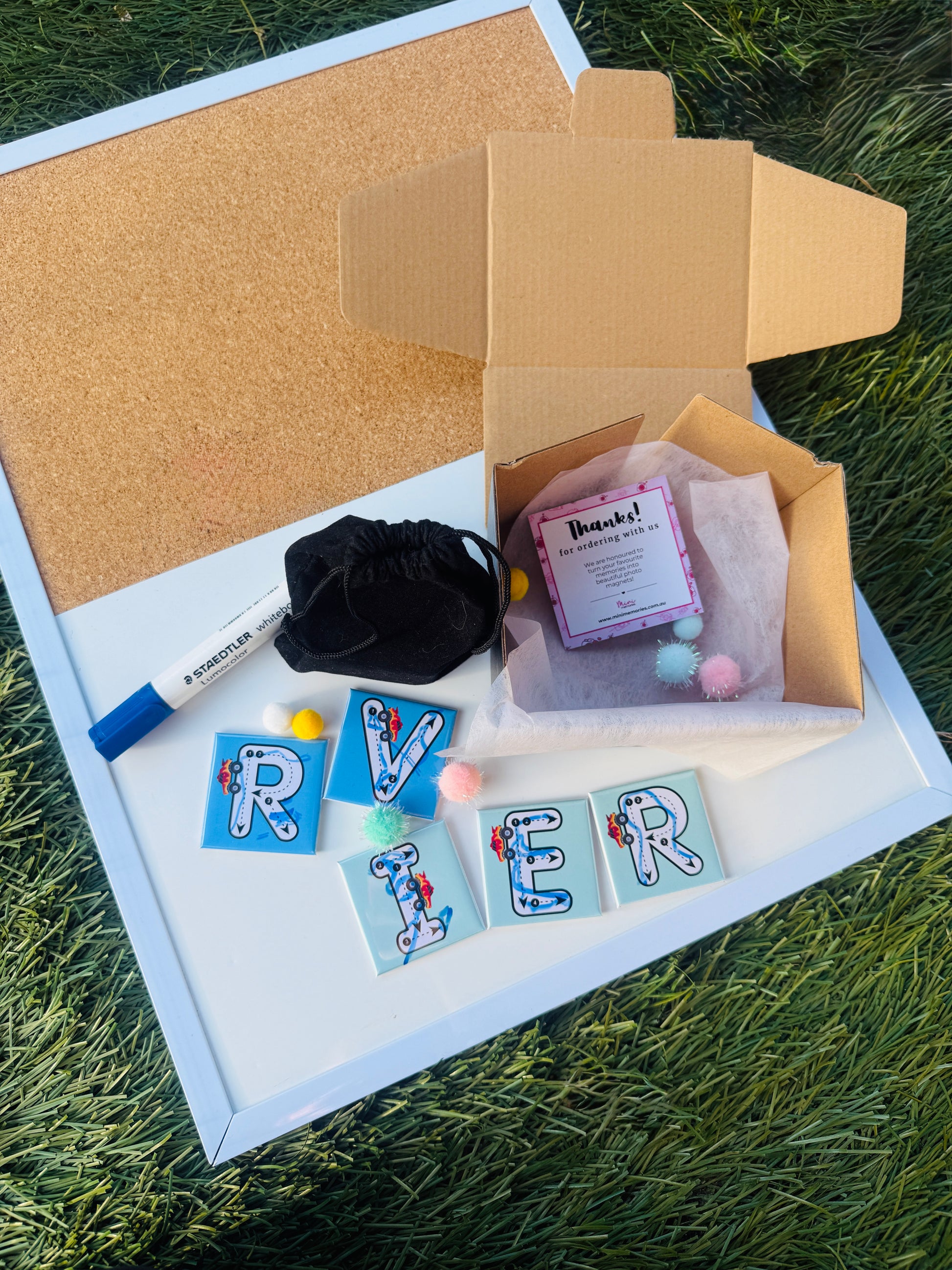 Gift Box with personalized letter tile magnets spelling 'RIVER' on a grassy surface