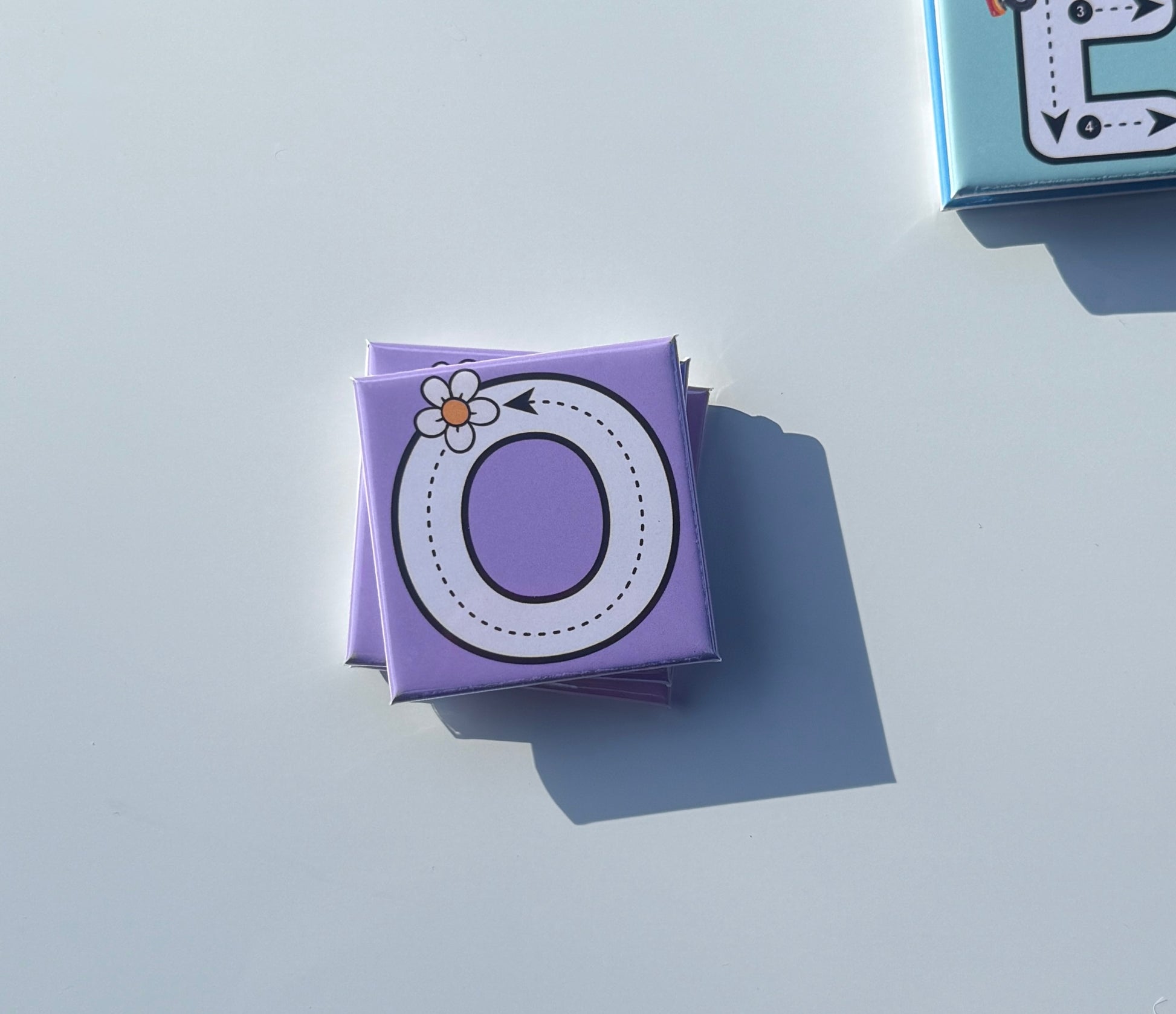 Purple letter 'O' box with a flower on a light gray background