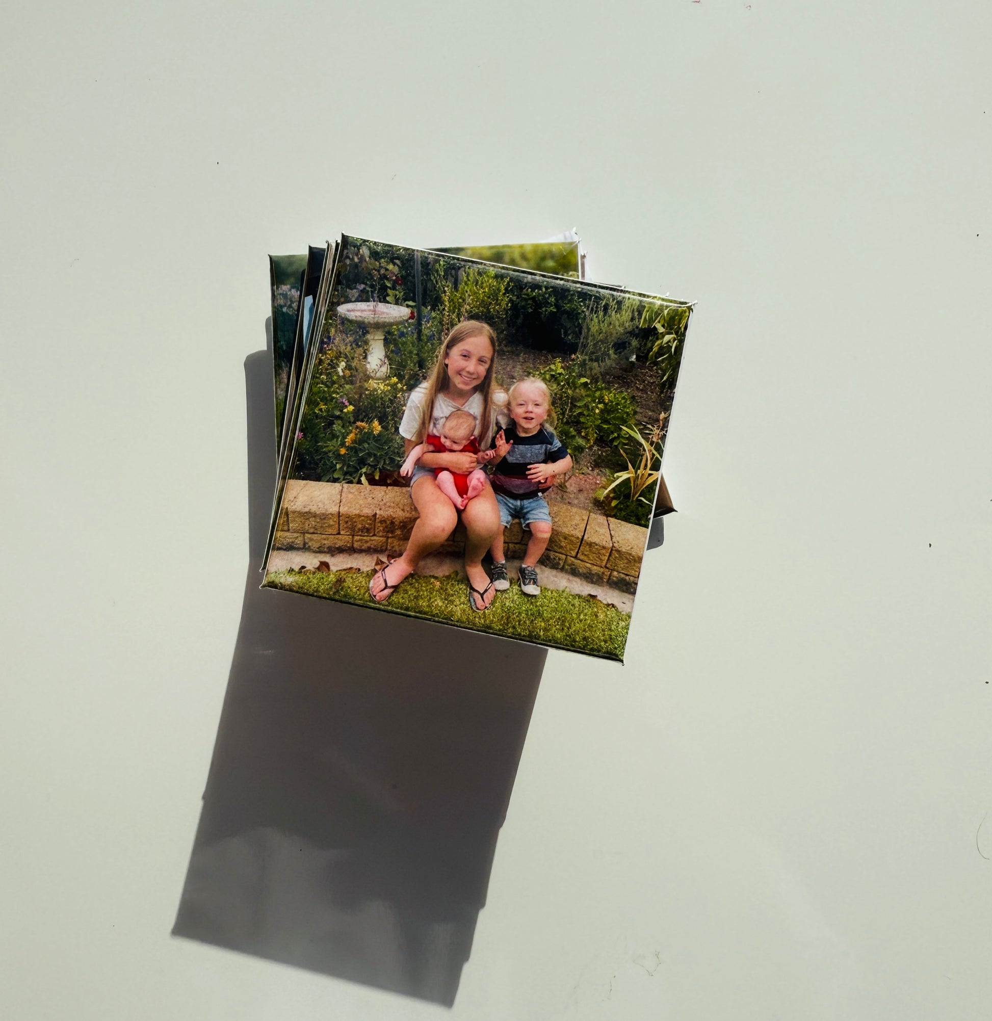  Custom photo magnet featuring three siblings sitting on a garden bench, used for personalized family photo gifts.

